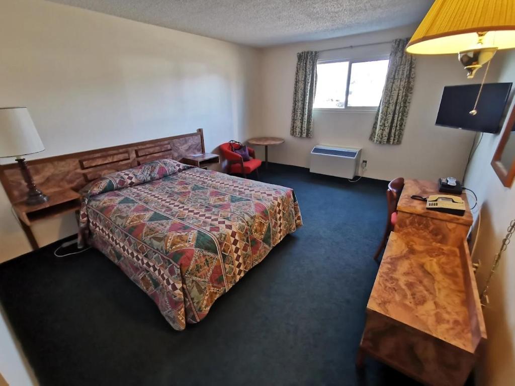 a hotel room with a bed and a window at Cataline Motor Inn in Fraser Lake