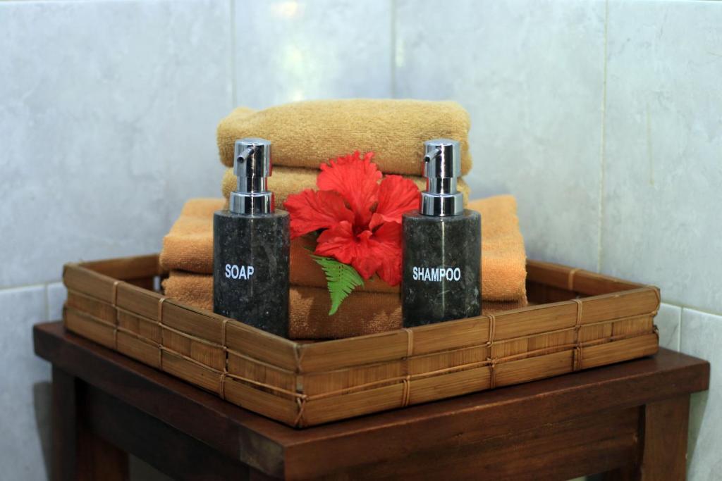 a basket with two bottles of soap and a red flower at Alam Terrace Cottages in Ubud