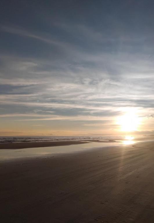 a sunset on a beach with the sun in the distance at Chalé Ahmar! in Jaguaruna
