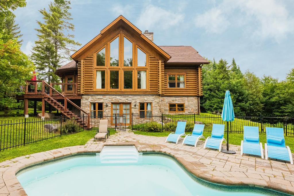 a log home with a pool and chairs and a house at Fiddler Lake Resort - Deer 61 in Mille-Isles