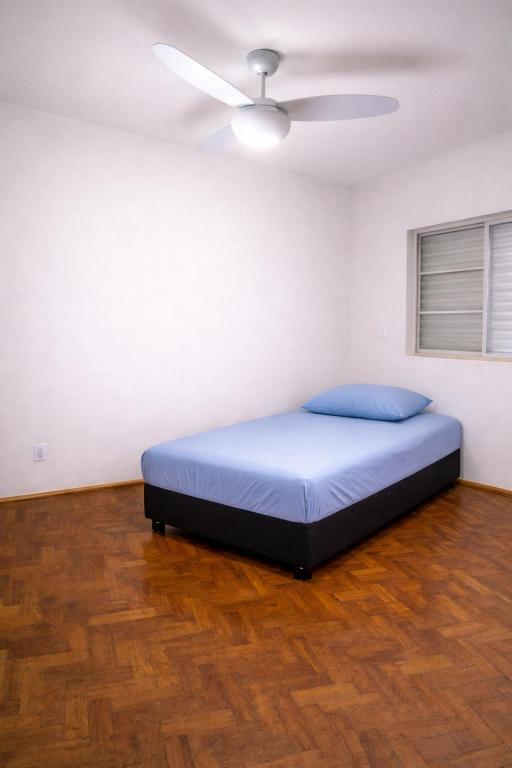 a bed in a room with a ceiling fan at Quarto em Barretos, simples com paz e harmonia in Barretos