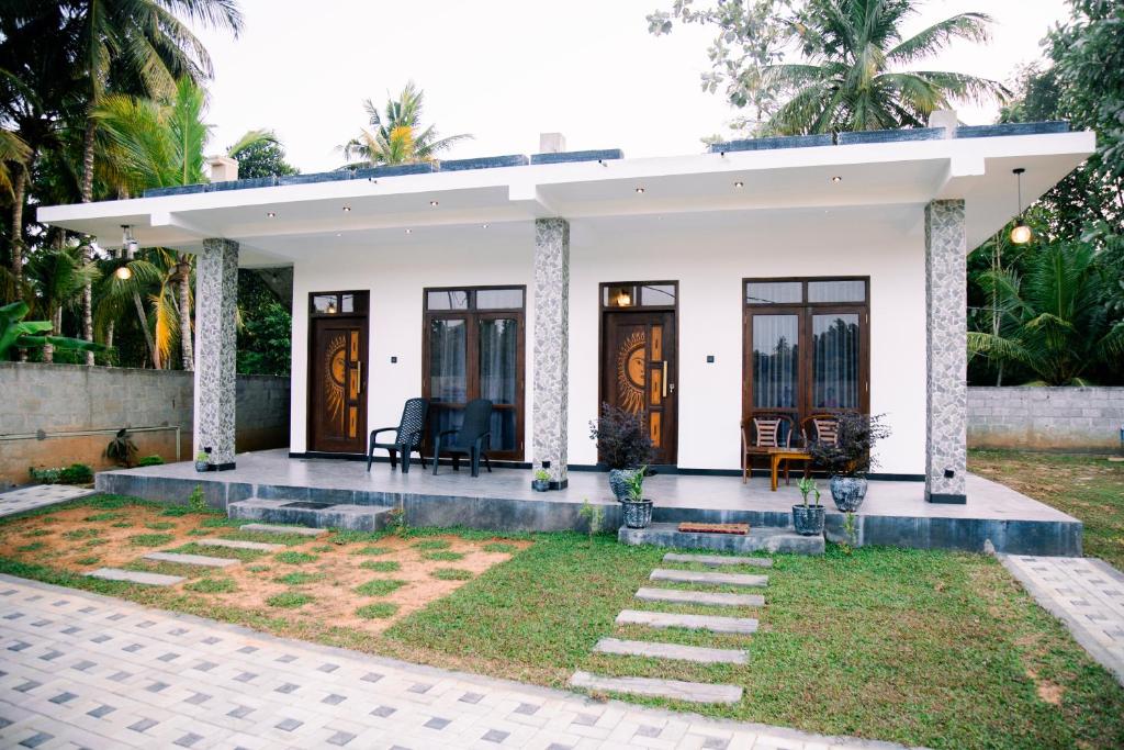 a white house with a patio and a yard at Paddy Breeze Villa in Batigama