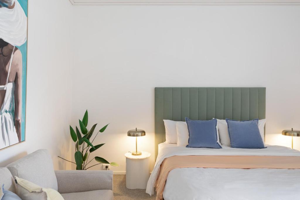 a bedroom with a bed with blue pillows and a chair at The Avalon in Mount Gambier