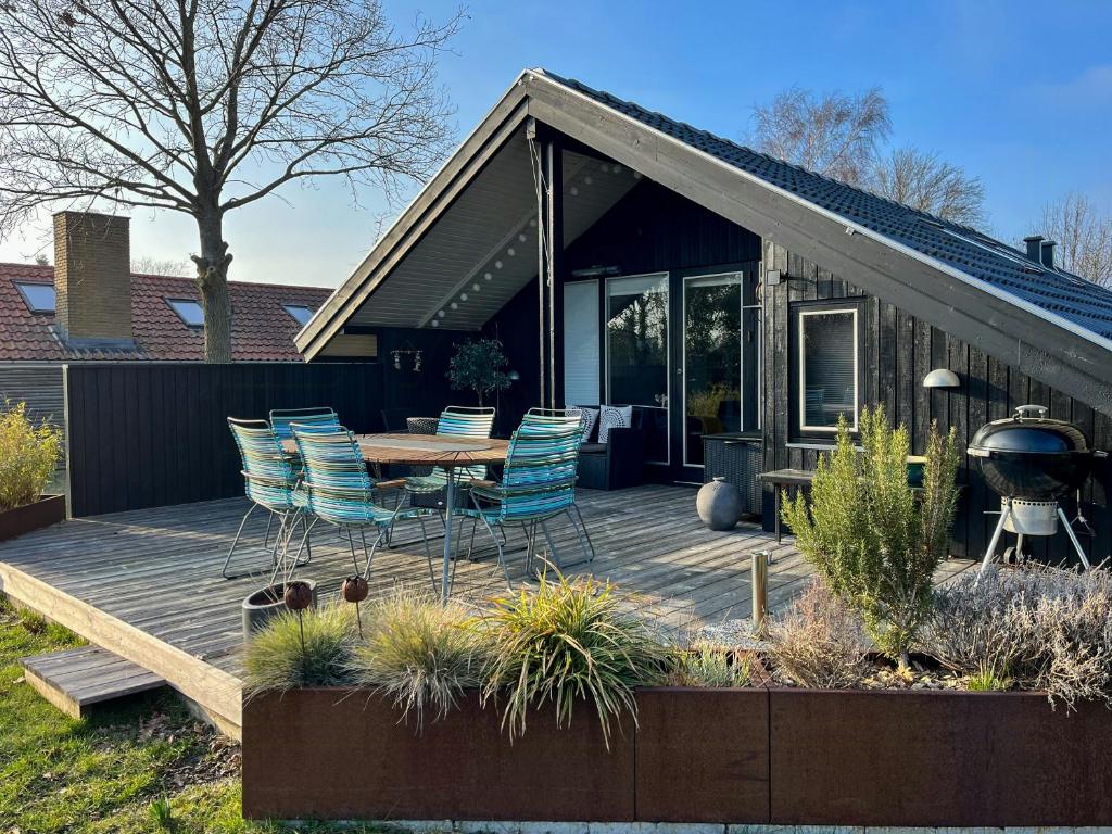 a deck with chairs and a table and a grill at Summer House With Authentic Charm On Enø in Karrebæksminde