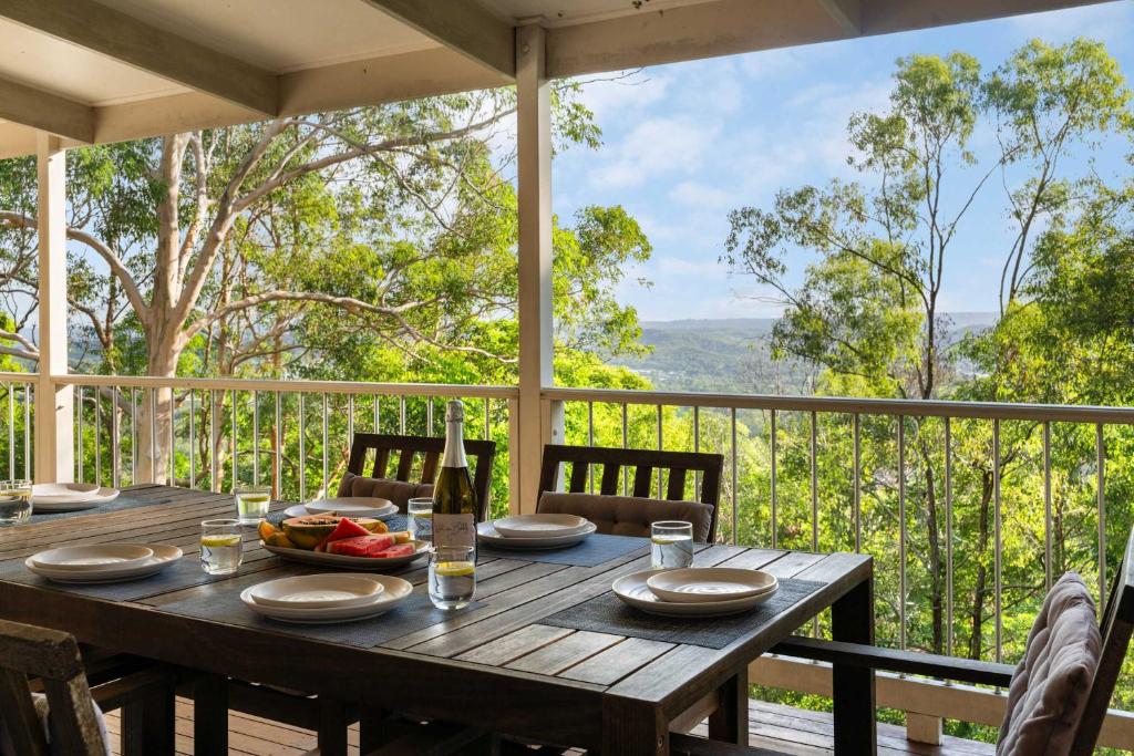 a wooden table with a bottle of wine on a balcony at Hinterland Tranquil Escape with Beautiful Views in Ninderry
