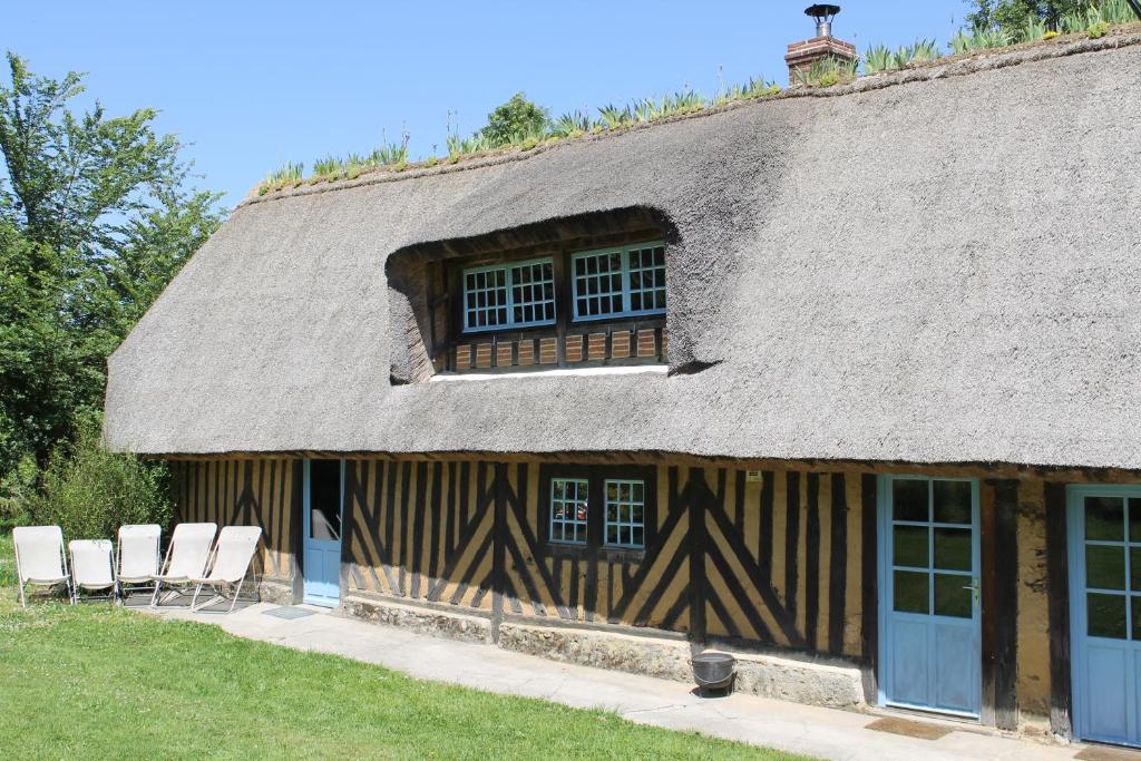 a building with two chairs and a thatch roof at La Chaumière aux Faisans in Ablon