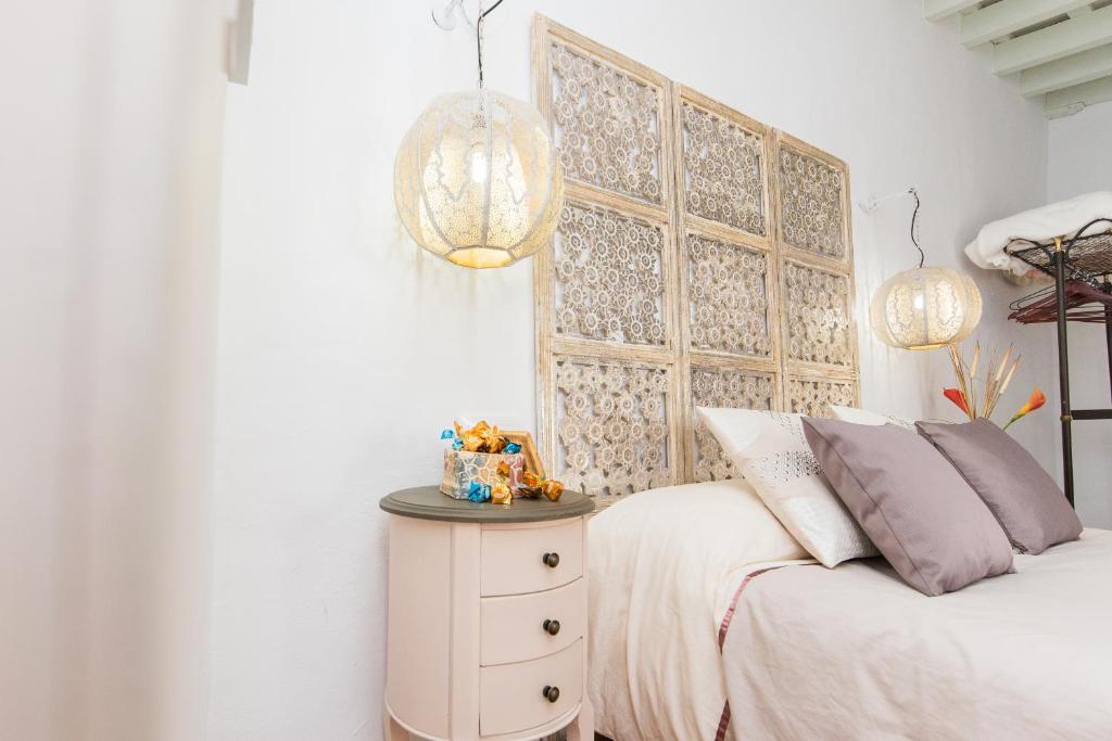 a white bedroom with a bed and a nightstand and lights at Casa Bodega Triana in Vejer de la Frontera