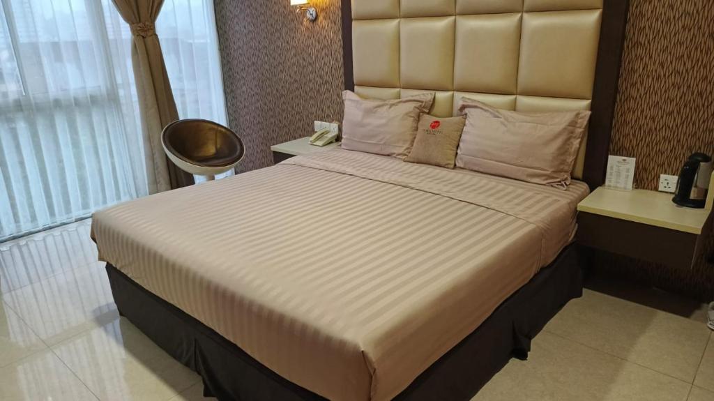 a bedroom with a large bed with a large headboard at osaka hotel batam in Nagoya