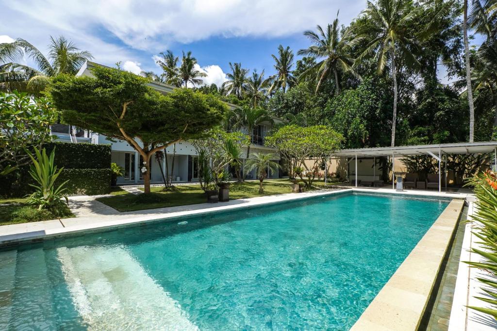 a swimming pool in front of a house with palm trees at Kimana Villa in Manggis