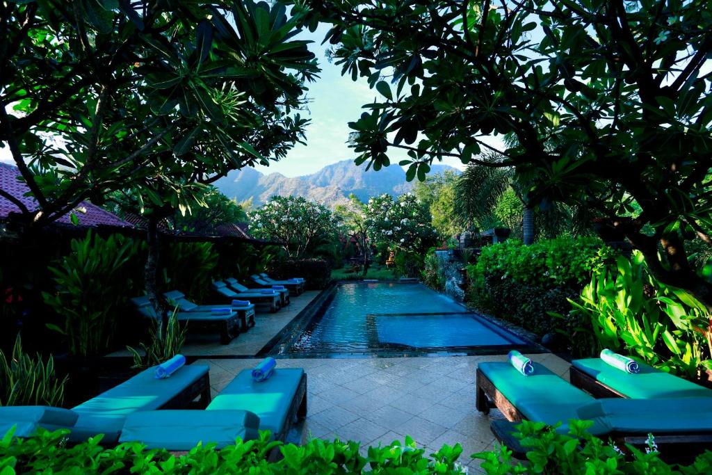 a swimming pool with blue lounge chairs in a resort at Taruna Boutique Homestay & Spa in Pemuteran