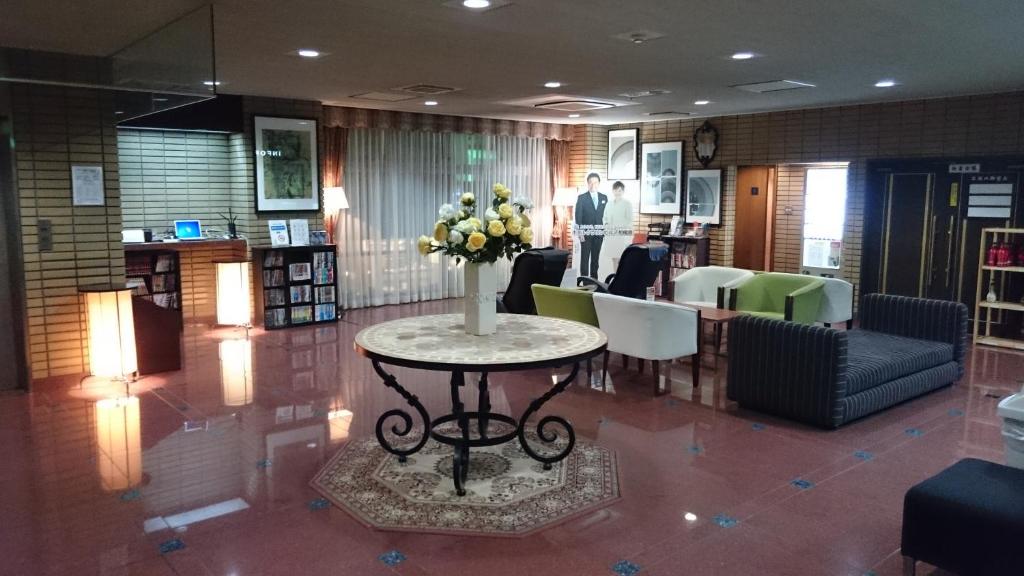 Hotel Crown Hills Sagamihara في ساغاميهارا: لوبي مع طاولة عليها إناء ورد