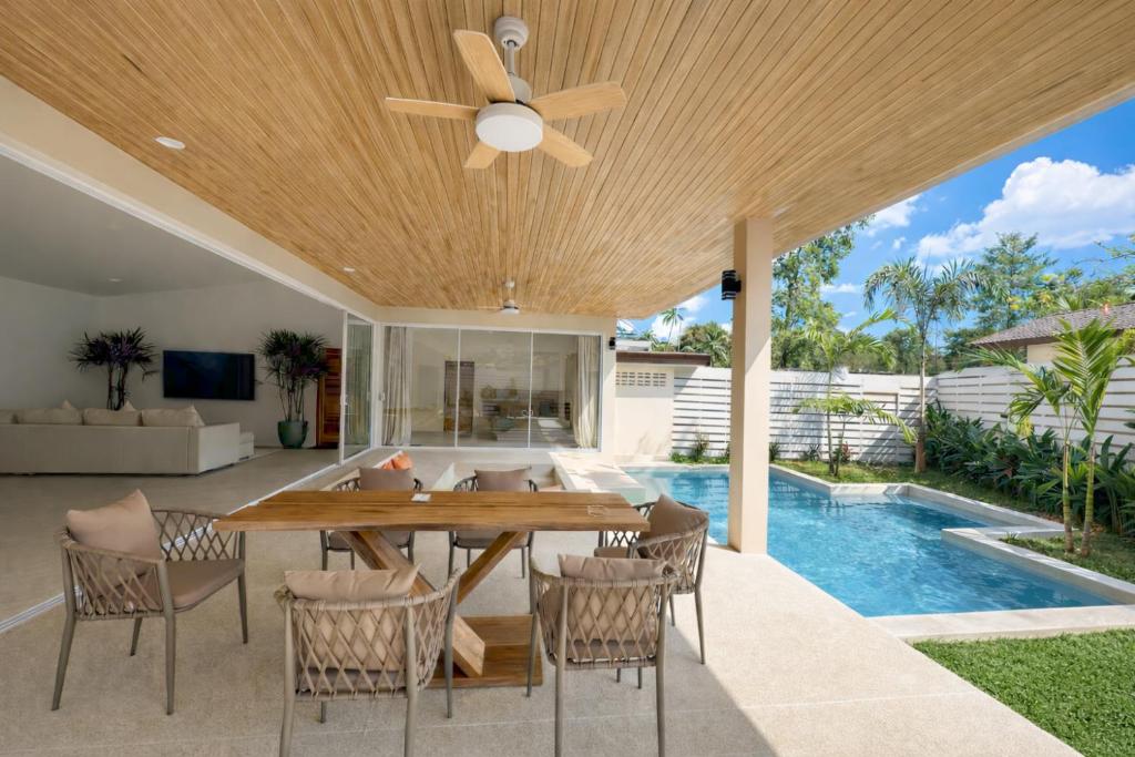 a patio with a wooden table and chairs and a pool at Modern Private Pool Villa - 3BR - Koh Phangan in Ko Phangan