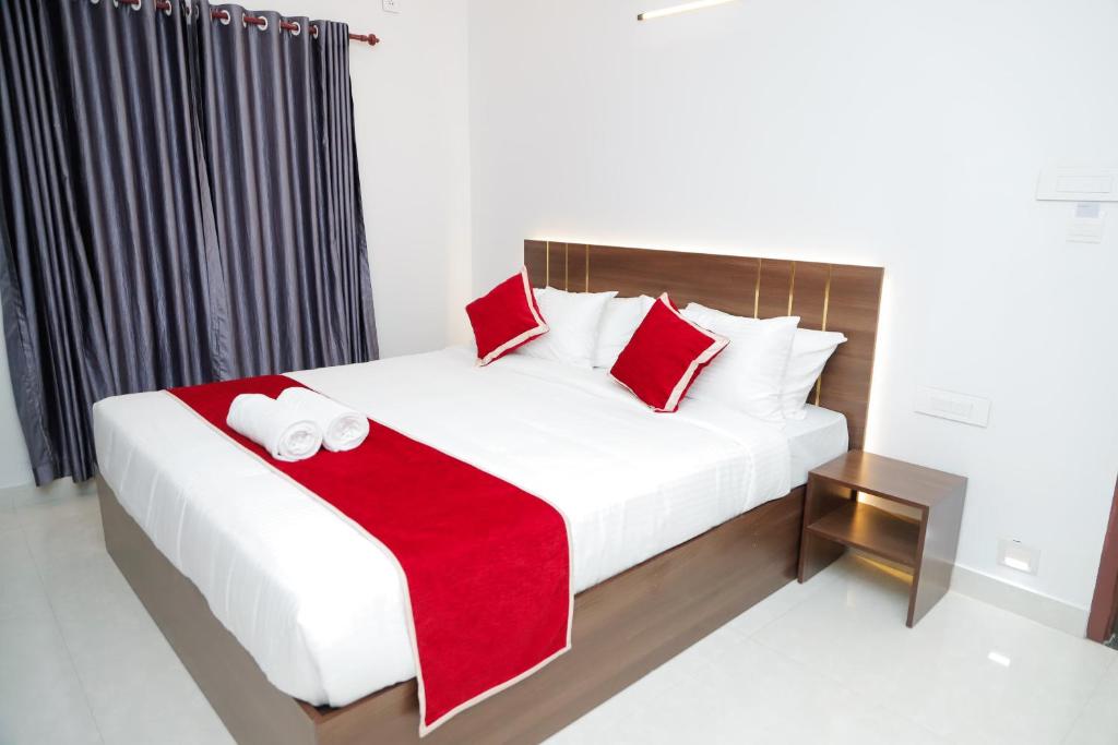 a bedroom with a bed with red and white pillows at Le Sancta homestay in Maraiyūr
