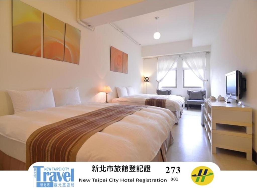 a hotel room with two beds and a television at Yago Inn in Tamsui