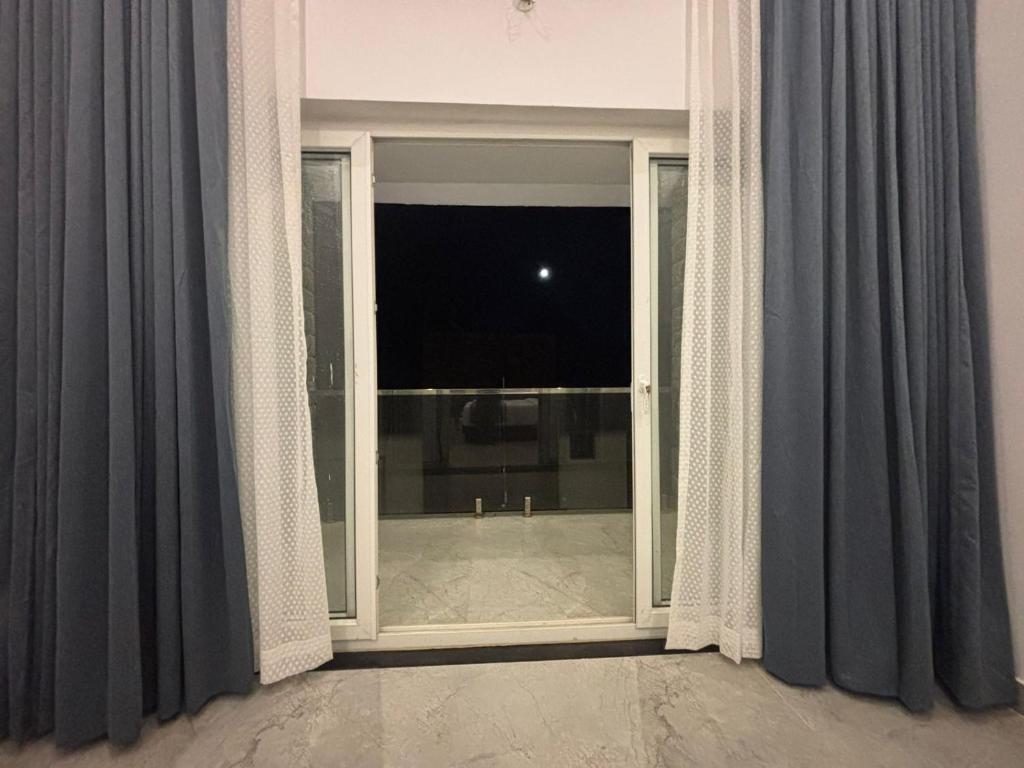 an open window with gray curtains and a view of a room at Kodai Square Homestay in Kodaikānāl