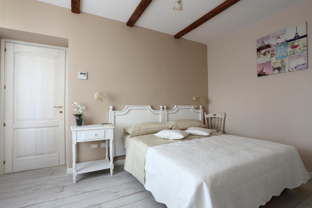 a white bedroom with a white bed and a table at Ambrosio Relais in Sorrento