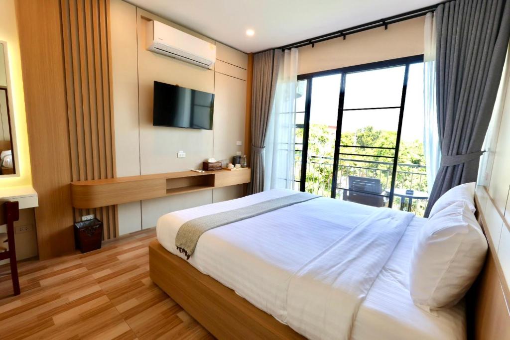a bedroom with a bed and a large window at KL Dawarika Mali Hotel in Ban Tai