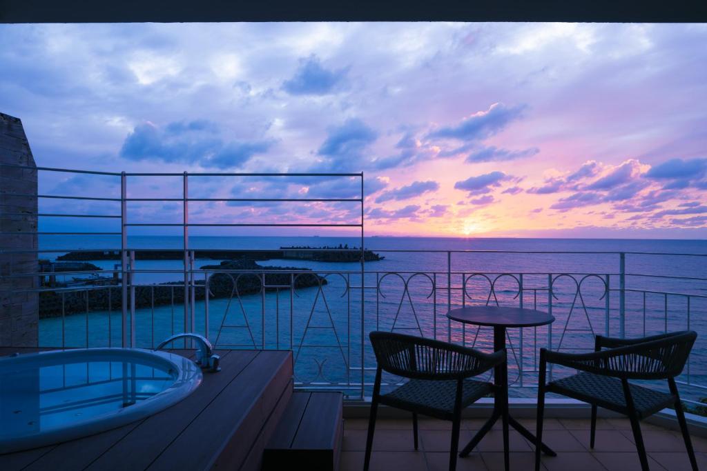 a balcony with a tub and chairs and a sunset at Anse Yomitan Toya in Yomitan