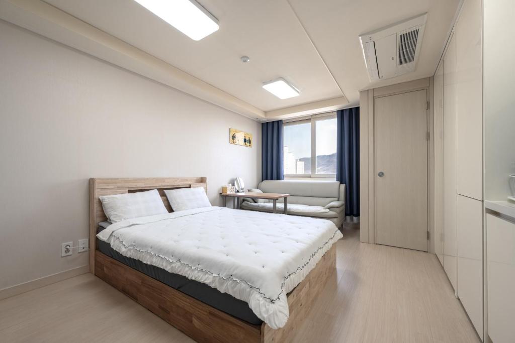 a bedroom with a bed and a couch and a window at 김천 포유스테이 in Oksan