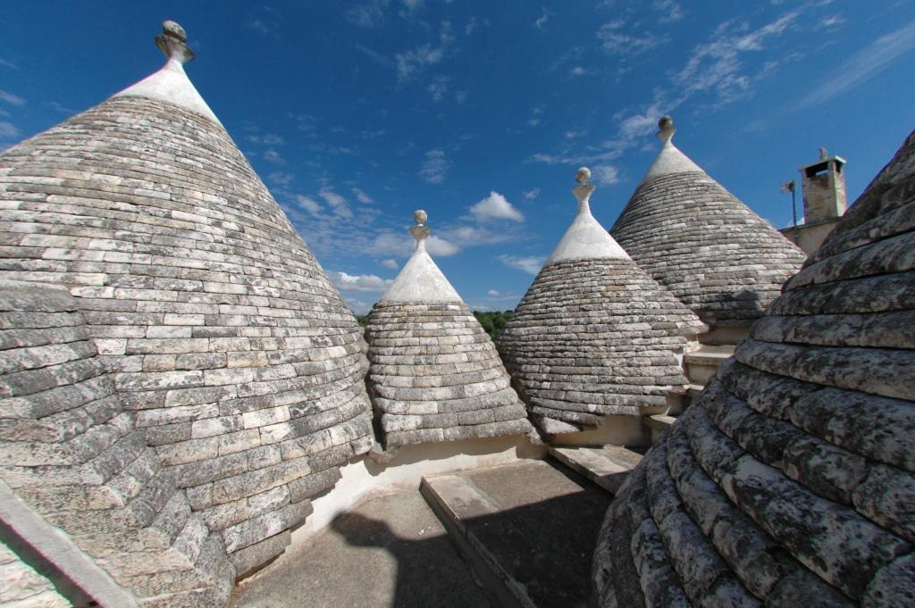 a row of stone roofs with a blue sky in the background at Trulli La Gufa in Ostuni