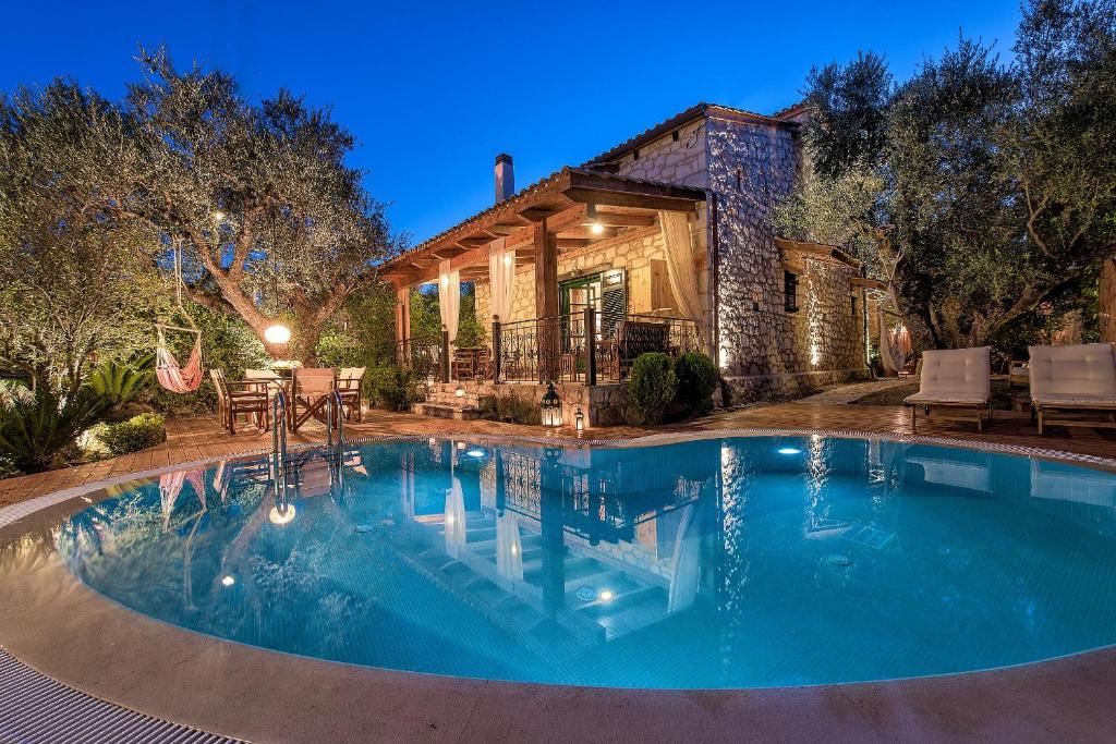 a swimming pool in front of a house at Anassa Villa in Mouzákion