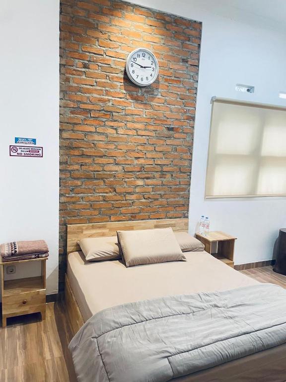 a bedroom with a bed and a brick wall with a clock at De Cabin Situjuah in Situjuhbatul