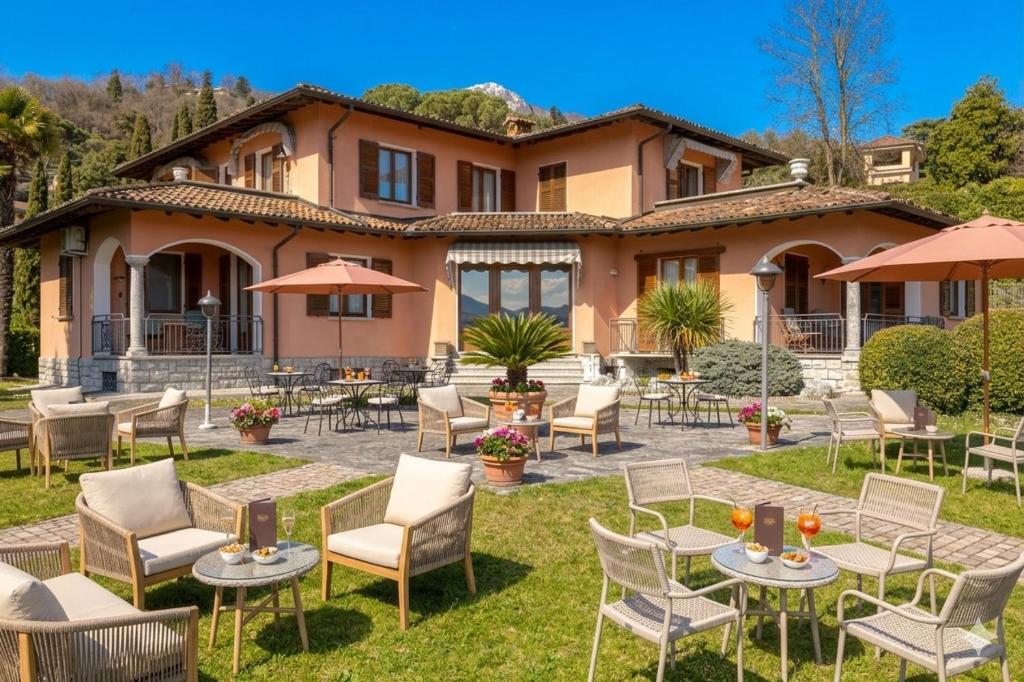 eine Terrasse mit Tischen und Stühlen vor einem Haus in der Unterkunft Hotel Royal in Menaggio