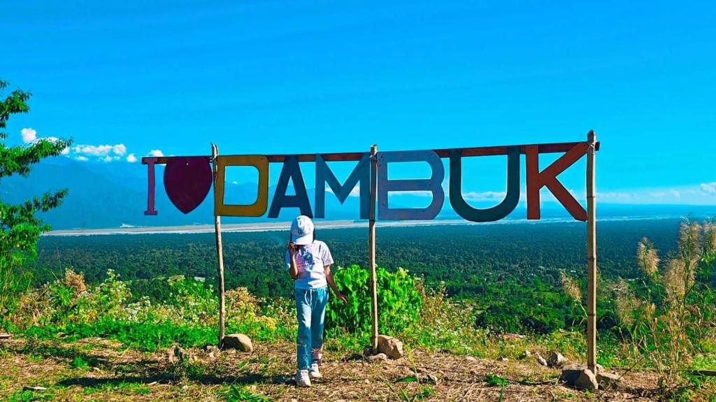 a person standing on top of a hill with a sign that reads dummy at Nature's Harmony Heaven in Dāmbuk