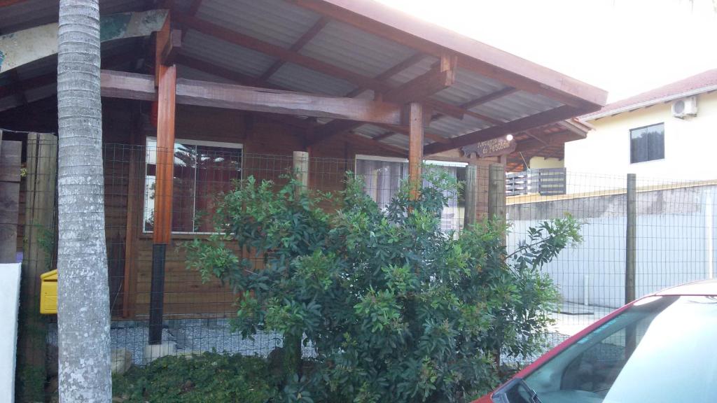 una casa de madera con un árbol delante en Porto Canoa Recanto do Pescador, en Penha