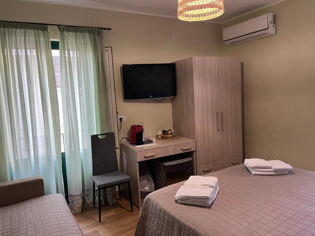 a bedroom with two beds and a desk and a television at A Casuzza in Pollina