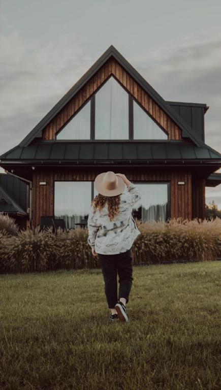 a woman walking in the grass in front of a house at oto.domki in Rokiciny Podhalanskie