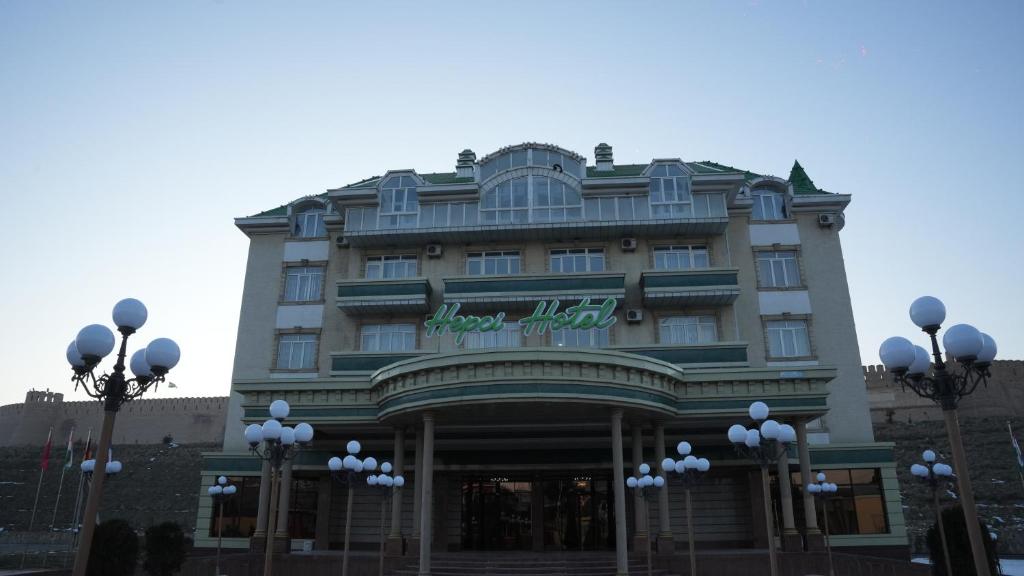 a building with a sign on the front of it at Hepci Hotel Istaravshan in Ŭroteppa