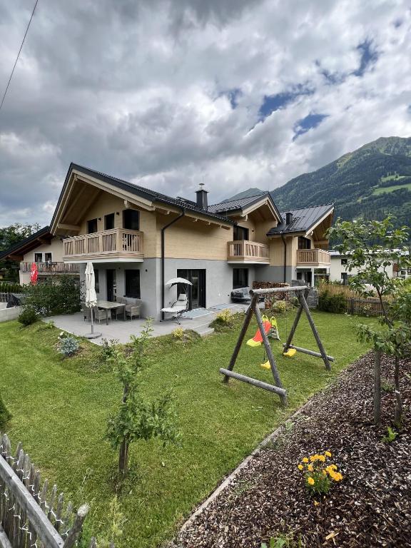 a house with a yard with a swing at Villa Chalet Schlossalm bis 9 Personen in Bad Hofgastein