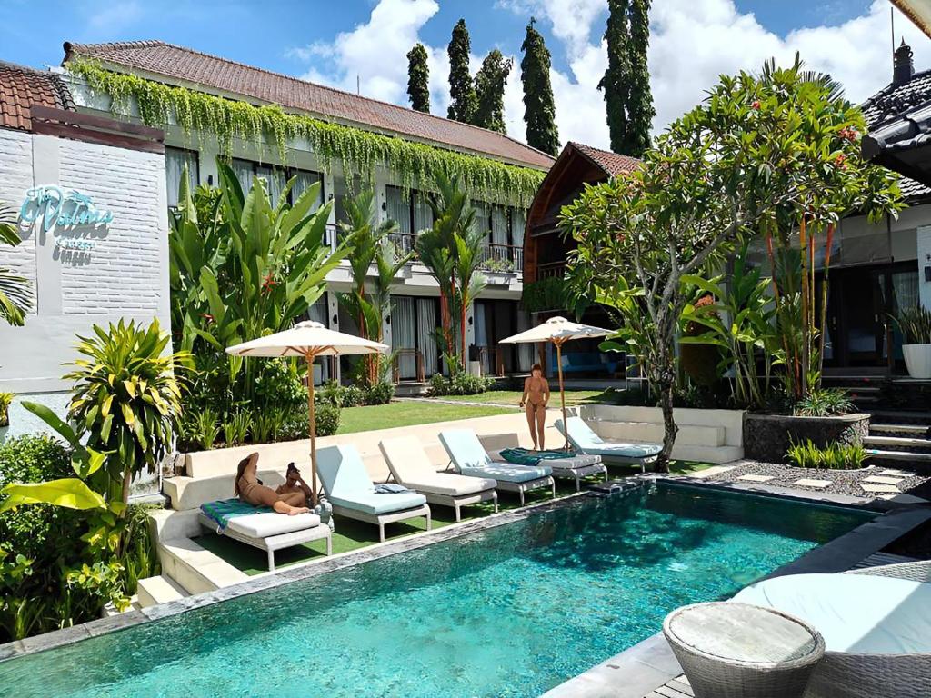 a pool with chairs and umbrellas next to a building at The Palms Canggu in Canggu