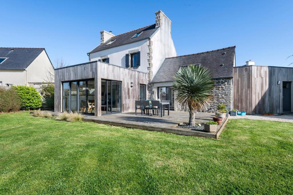 a house with a patio with a palm tree in the yard at Ker Helo-ana in Brignogan-Plage