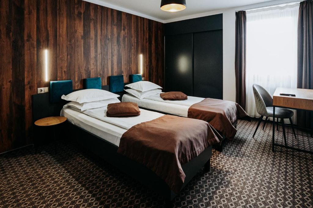 a hotel room with two beds and a desk at Pension Belascu in Sibiu