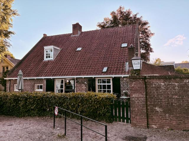 a brick house with a red roof and a street light at B&B Het Gasthuys in Amerongen