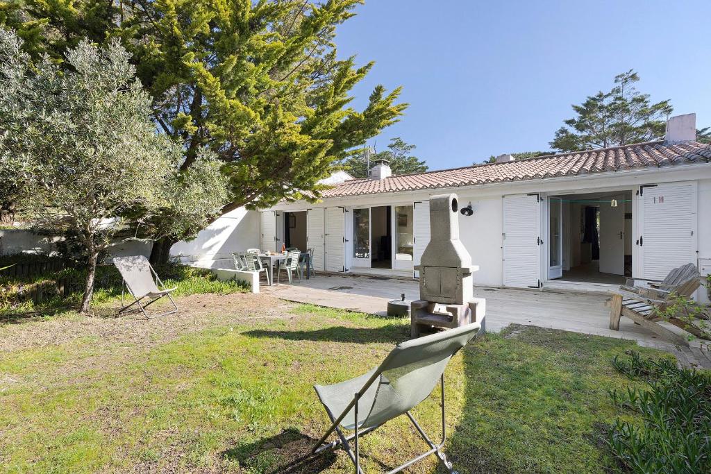 a house with two lawn chairs in the yard at Ile de Noirmoutier - Maison T4 in La Guérinière