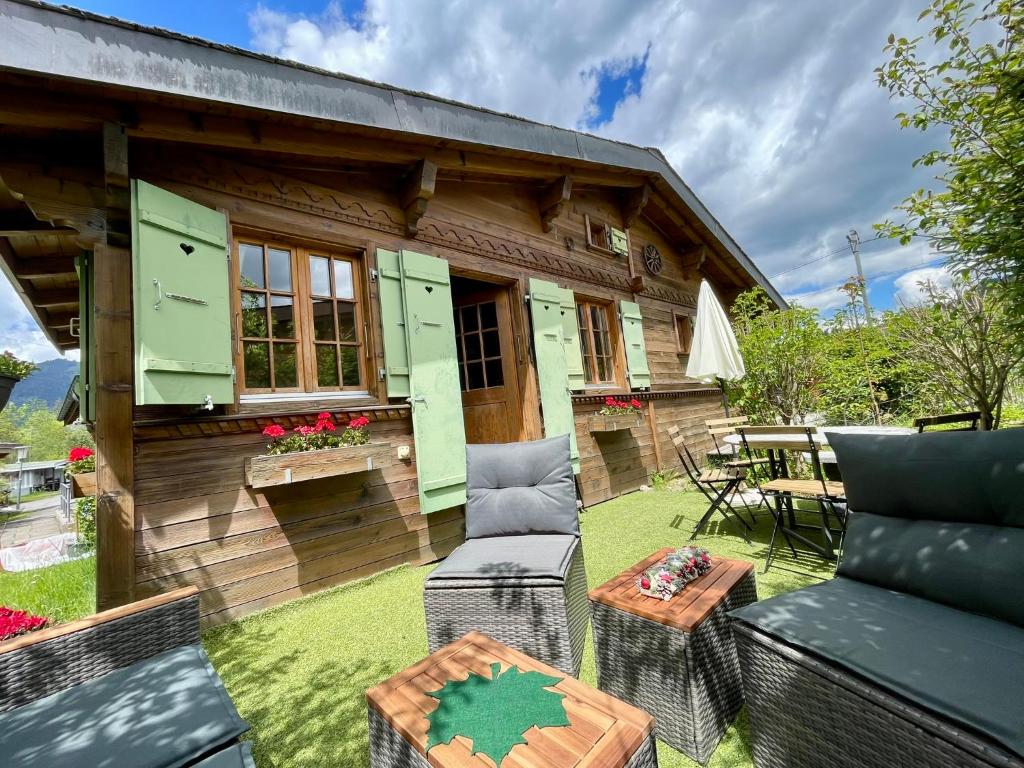 a small wooden house with a patio and a table at Gstaad Chalet in Gstaad