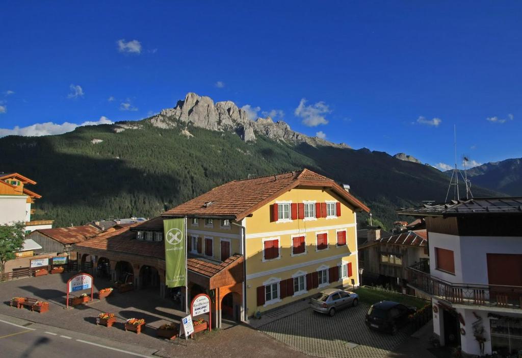 a building in a town with a mountain in the background at Tony Sport appartamenti in Vigo di Fassa