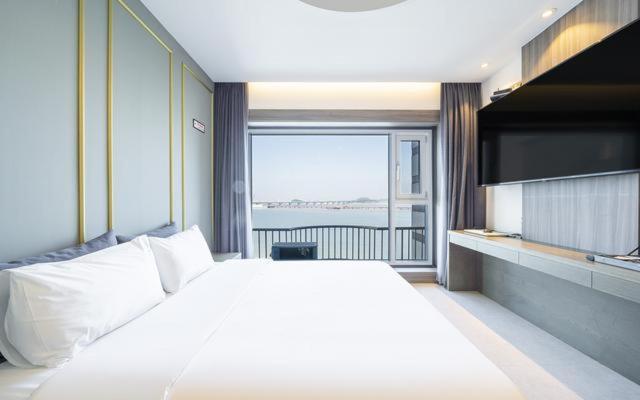 a bedroom with a large white bed and a large window at Dangjin Dubai Hotel in Dangjin