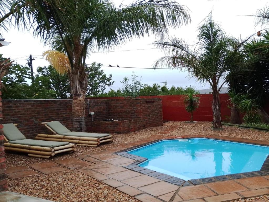 a swimming pool in a yard with two lounge chairs at Colchester Suites - Travel Addo Group in Cannonvale