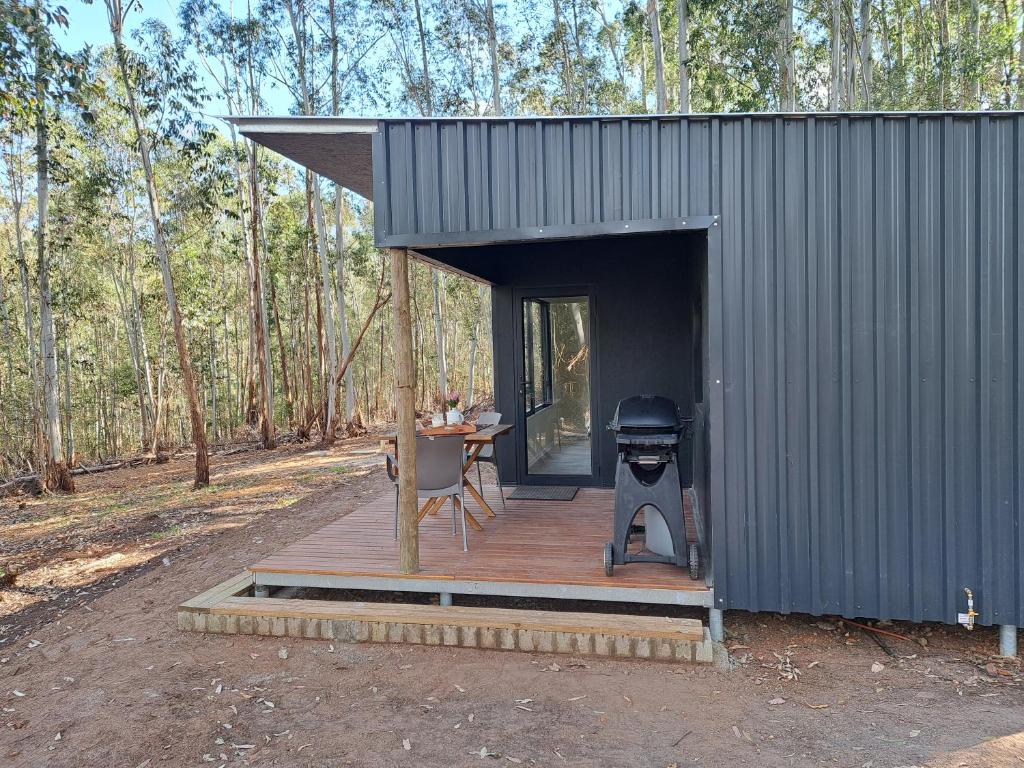 a cabin with a table and a grill in the woods at Zest Forest Retreat in Great Brak River