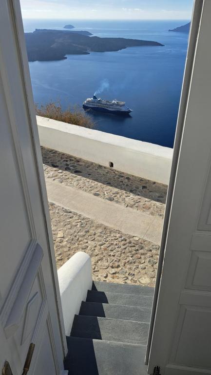 a view of a ship in the water from a door at Yposkafo Suites - Villa - Santorini in Fira
