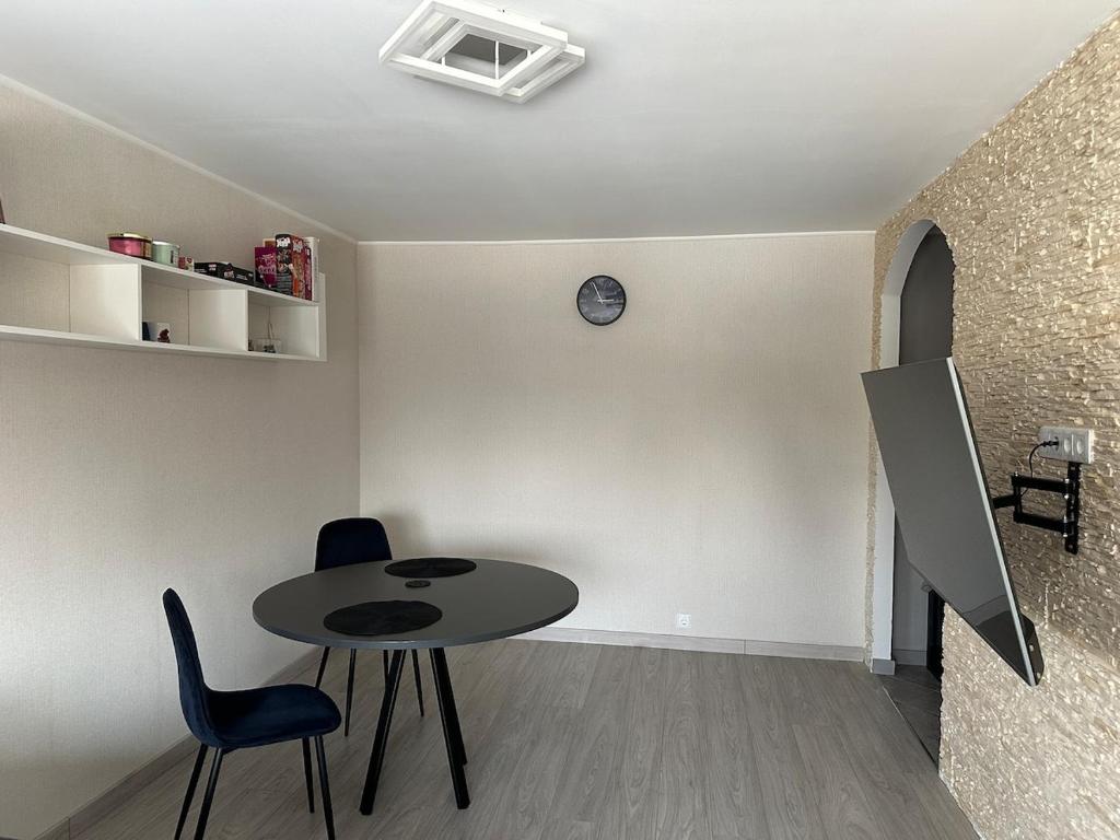 a room with a table and chairs and a clock on the wall at Central Cozy Apartment in Ludza
