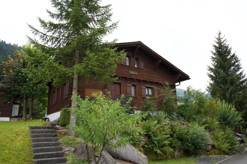 a wooden house with a tree in front of it at Chalet Enzian Wirzweli in Dallenwil