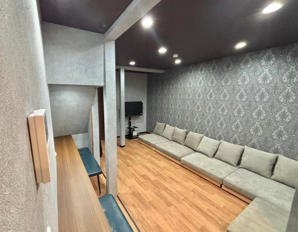 a living room with a long couch and a tv at HoTTOSTAY旭 in Nishi-biwajima
