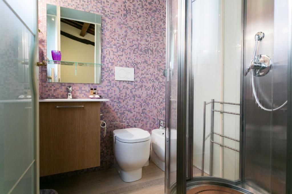 łazienka z toaletą, umywalką i lustrem w obiekcie Relais Pacinotti Apartments w Pizie