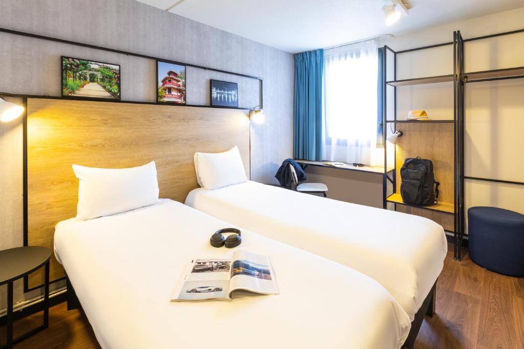 Zwei Betten in einem Hotelzimmer, auf dem Bett liegt ein Buch. in der Unterkunft ibis Epinal Centre in Épinal