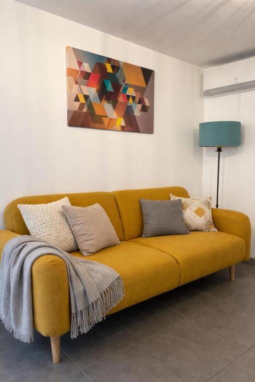 a yellow couch in a living room with a painting at Coeur de pierre in Vallon-Pont-dʼArc